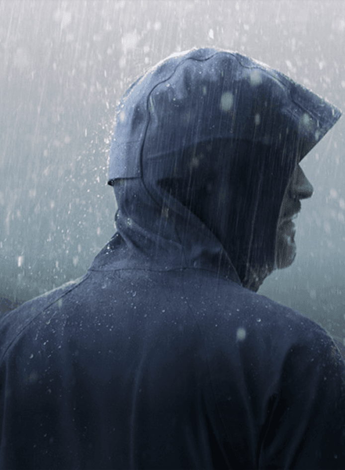 Guy in blue jacket with a lot of rain showing waterproof EMPEL product